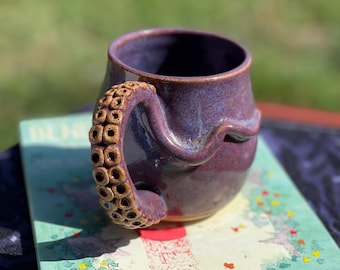 Tazza in ceramica a forma di tentacolo con smalto viola testurizzato.