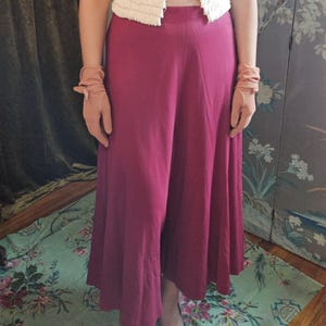 May include: Cream-colored, short-sleeved jacket with a textured, fringed design. Paired with wide-leg, burgundy pants and matching gloves. The outfit is completed with brown shoes.