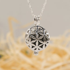 Puede incluir: Un collar de plata con un colgante redondo que presenta un diseño geométrico de la flor de la vida.