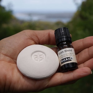 May include: A white ceramic diffuser with a star-shaped design and a small brown glass bottle of essential oil labelled "Bush Blend" with the text "Halkab Organics".