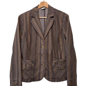 May include: Brown striped blazer with a notched collar, button closure, and two front pockets. The blazer is hanging on a wooden hanger against a white background. The jacket has a vertical striped pattern in shades of brown and tan.