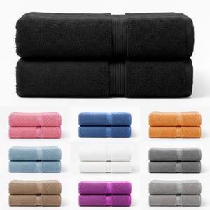 May include: A selection of folded bath towels in a range of colours: black, pink, blue, orange, light blue, white, grey, brown, and purple. Each set of towels is neatly stacked, displaying a soft, textured appearance.