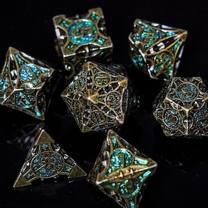 May include: A set of seven polyhedral dice featuring an intricate, dark metallic cage-like frame with a weathered finish. Each die face contains a recessed, shimmering teal glitter inlay. The numbers are embossed within circular patterns on the faces.