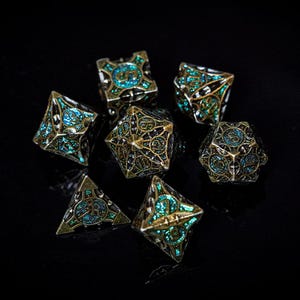 May include: A set of seven antique-style polyhedral dice. The dice have a bronze finish with intricate designs and teal and blue accents. The dice are arranged on a black surface, with a focus on the details of each die.