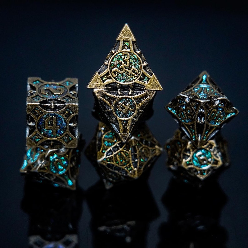 May include: Set of four ornate, multi-sided dice in bronze and teal. The dice have intricate geometric designs and are likely used for tabletop gaming. The dice are displayed on a dark reflective surface.