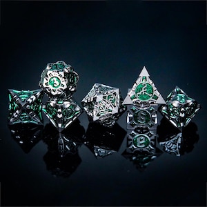 May include: A set of five intricate metal polyhedral dice featuring a silver-toned skeletal frame with a vibrant green marbled inlay. Each die displays clear numerical engravings and geometric cutouts, showcasing a complex, hollow-core design.