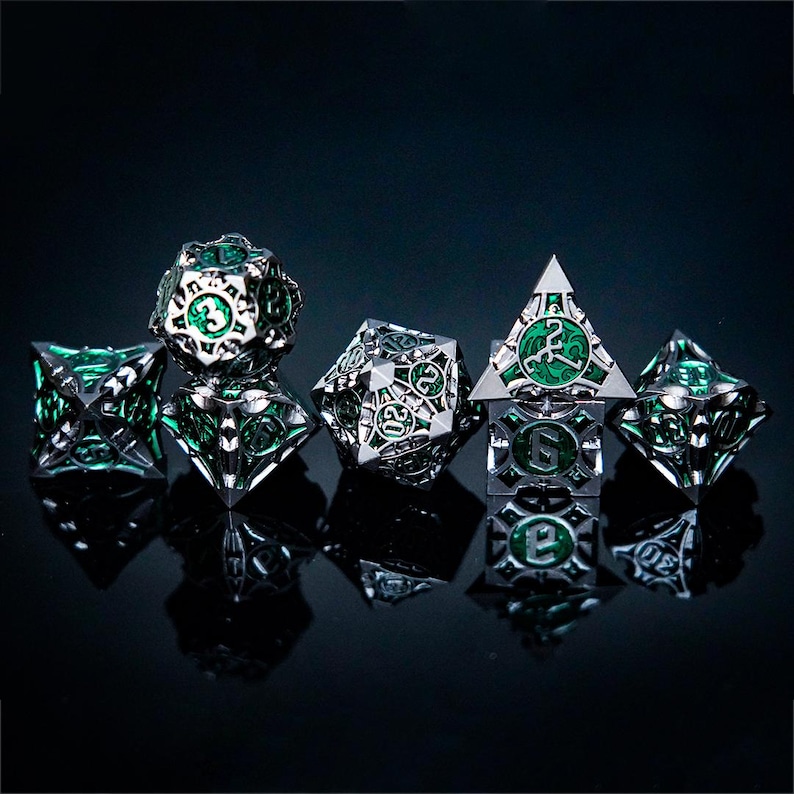 May include: A set of five intricate metal polyhedral dice featuring a silver-toned skeletal frame with a vibrant green marbled inlay. Each die displays clear numerical engravings and geometric cutouts, showcasing a complex, hollow-core design.