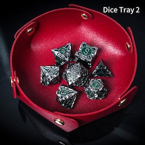May include: A red, circular, collapsible tray with gold-coloured metal snaps, containing a set of seven intricate, silver-toned metal polyhedral dice with green enamel inlays. The text 'Dice Tray 2' is visible in the upper right corner.