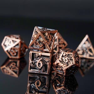 May include: A set of copper-colored metal dice for tabletop games. The dice have intricate designs and visible numbers. The set includes various shapes, such as a d20, d12, and d6, with a reflective surface.