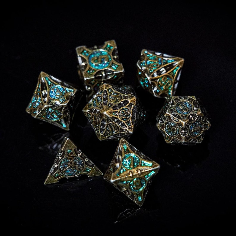 May include: A set of seven polyhedral dice featuring an intricate, dark metallic cage-like frame with a weathered finish. Each die face contains a recessed, shimmering teal glitter inlay. The numbers are embossed within circular patterns on the faces.