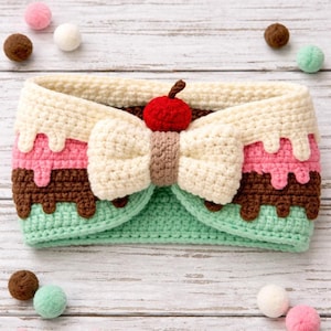 May include: A handmade crochet headband in the shape of an ice cream sundae. The headband features a cream-colored top with dripping details, pink and brown layers, and a mint green base. A cherry tops the bow.