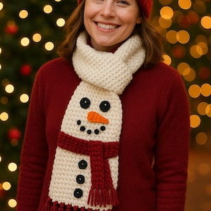 May include: A woman wearing a red knit hat and sweater, with a cream-colored snowman scarf. The scarf has black button eyes, a carrot nose, and a red scarf and fringe. The background features blurred Christmas lights.