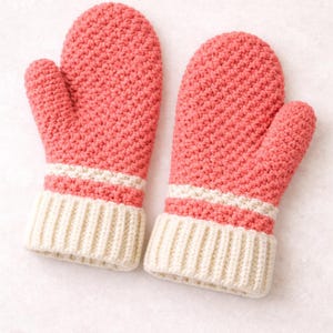 May include: A pair of coral-colored mittens with a ribbed ivory cuff and two ivory stripes. The mittens are made of a knitted material, perfect for keeping hands warm in cold weather.