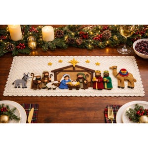 Puede incluir: Camino de mesa de ganchillo color crema con un pesebre. La escena incluye figuras de María, José, el niño Jesús, los tres reyes magos, un burro, un camello y una oveja. El camino de mesa tiene un borde festoneado y estrellas doradas.