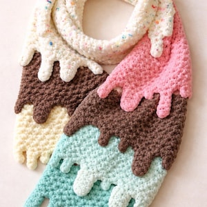May include: A whimsical, handmade crochet scarf designed to resemble melting ice cream. The scarf features sections of white with colorful sprinkles, pink, brown, light blue, and cream colors, with dripping edges. The scarf is a unique accessory.