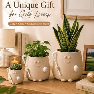 Puede incluir: Tres macetas de cerámica beige con forma de personajes sonrientes que sostienen palos y pelotas de golf blancos. Las macetas contienen plantas verdes, incluyendo una suculenta y una sansevieria. Texto: A Unique Gift for Golf Lovers, Cute, Cozy, Conversation Piece.