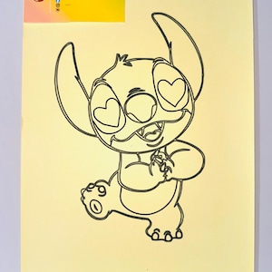 Puede incluir: Un dibujo de contorno negro del personaje Stitch de Lilo & Stitch, con ojos en forma de corazón, sobre un fondo amarillo claro. El personaje está en una pose juguetona. Una etiqueta amarilla en la esquina superior izquierda dice "SANDRYLIX SAND PAINTING".