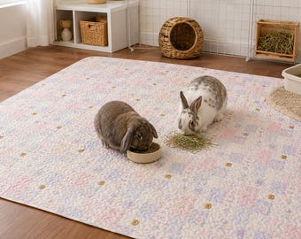 Peut inclure: Un grand tapis de sol rectangulaire avec un motif répétitif pastel rappelant un patchwork dans des tons rose, bleu et blanc. Deux lapins sont sur le tapis, l'un mangeant dans un petit bol beige et l'autre mangeant du foin.