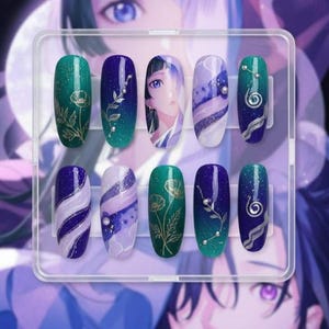 Op de afbeelding: Een set van tien kunstnagels in een doorzichtige plastic doos. De nagels hebben verschillende ontwerpen, waaronder bloemmotieven, abstracte wervelingen en een anime-stijl portret, in tinten groen, blauw, paars en wit. Sommige nagels hebben glitter of kleine versieringen.