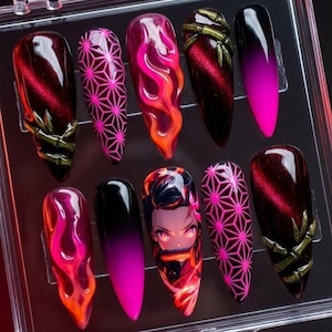 Puede incluir: Un conjunto de diez uñas artificiales largas en forma de almendra. Los diseños incluyen patrones geométricos, efectos de llama y arte de personajes de estilo anime. Los colores incluyen rosa, rojo, negro y detalles dorados.