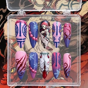 May include: A set of ten long, almond-shaped press-on nails in a clear plastic case. The nails feature various designs, including anime-inspired artwork, snowflakes, and abstract patterns in shades of pink, purple, and blue. The case has a decorative background.