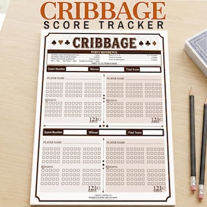 Può includere: Un segnapunti di cribbage con la parola "CRIBBAGE" in alto. Il foglio segnapunti ha spazi per i nomi dei giocatori, i numeri di gioco e i punteggi. Un mazzo di carte e due matite sono accanto al foglio segnapunti.