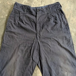 May include: Dark navy blue pants with a button closure and pleats at the waist. The pants have a relaxed fit and appear to be made of a soft, durable fabric. The pants are a solid color and have a slightly faded appearance.