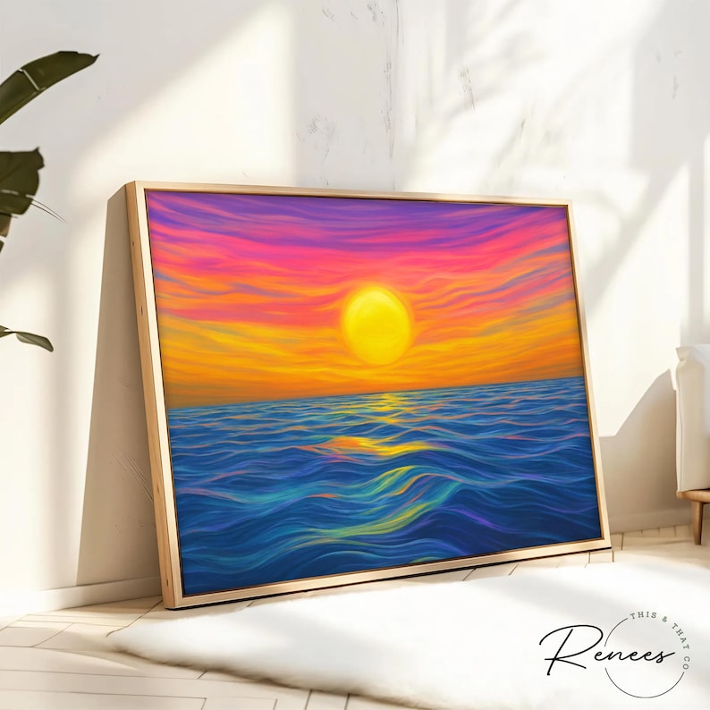 May include: A framed art print depicts a vibrant sunset over the ocean. The artwork features a large yellow sun, orange and pink sky, and blue water. The frame is a light wood color. The artist's signature is in the bottom right corner.
