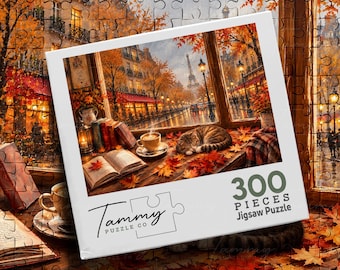 May include: A 300-piece jigsaw puzzle box featuring an illustration of a cat sleeping on a windowsill next to a cup of coffee and an open book. The scene depicts a rainy Paris street with the Eiffel Tower in the distance, surrounded by autumn leaves.
