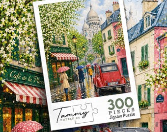 May include: A 300-piece jigsaw puzzle by Tammy Puzzle Co featuring a Parisian street scene with a red car, people with umbrellas, a cafe named Cafe de la Place, and the Sacre-Coeur basilica in the background under a bright, cloudy sky.