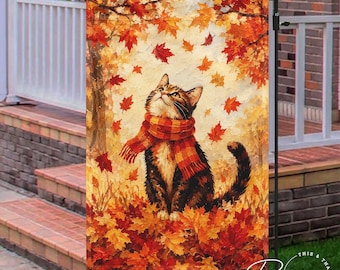 May include: A rectangular garden flag featuring a painting of a brown tabby cat wearing a red and orange plaid scarf. The cat sits amidst a vibrant scene of falling autumn maple leaves in shades of red, orange, and yellow against a light background.
