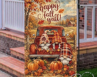 May include: A rectangular garden flag featuring a red vintage truck carrying three gnomes wearing plaid hats. The scene includes orange pumpkins, autumn leaves, and a farmhouse in the background. The text "happy fall y'all!" is printed in brown script.