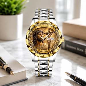 Könnte beinhalten: Eine zweifarbige Armbanduhr in Silber und Gold mit einem runden Zifferblatt, das ein Porträt von Jesus und eine Kreuzigung zeigt. Das Zifferblatt enthält den Text "THERE IS NO GREATER LOVE THAN THIS", den Namen "DAVID" und eine Datumsanzeige.