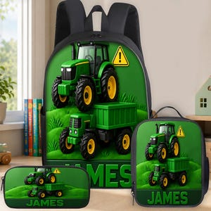 Puede incluir: Un conjunto de mochila, bolsa de almuerzo y estuche negros con un gráfico de un tractor verde con remolque sobre una colina de hierba y una señal de advertencia amarilla. El nombre JAMES aparece en grandes letras verdes en cada pieza.