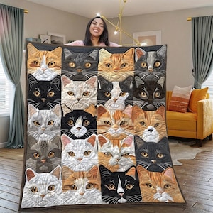 Puede incluir: Una manta acolchada con un patrón repetido de caras de gatos en varios colores. Las caras de los gatos son de color naranja, negro, blanco y gris. La manta se muestra en un salón.