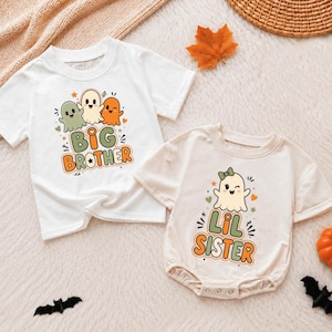 May include: A white short-sleeved t-shirt with a graphic of three ghosts and the text BIG BROTHER, alongside a cream-colored short-sleeved baby bodysuit with a graphic of a single ghost wearing a bow and the text LIL SISTER in orange and green.