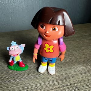 May include: A white ceramic mug with a black handle and the text "But First, Coffee" in a black, bold font. The mug is sitting on a wooden surface. The mug is approximately 4 inches tall.