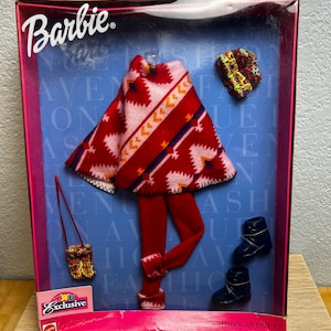 Puede incluir: Conjunto exclusivo Barbie Fashion Avenue. El conjunto incluye un poncho estampado en rojo y rosa, leggings rojos, un gorro a juego, un bolso pequeño y dos pares de botas negras. El embalaje es rosa y azul.