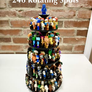 Peut inclure: Un présentoir rotatif noir à cinq niveaux circulaires accueillant de nombreuses petites figurines en plastique, avec une figurine bleue au sommet. Le texte 246 Rotating Spots est visible au-dessus du support, qui présente une variété de personnages colorés.