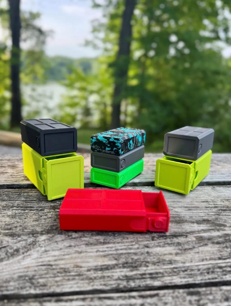 Pu&ograve; includere: Una collezione di contenitori rettangolari con cassetti scorrevoli. Il set include un contenitore rosso, due contenitori verde lime con coperchi grigio scuro e una pila di tre contenitori in nero, grigio e con motivo mimetico blu e nero.