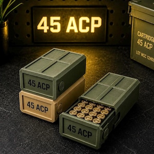 May include: Two rectangular olive green and tan storage boxes labeled 45 ACP, designed to resemble ammunition crates. One box is closed, while the other is open, revealing a grid of brass-colored 45 ACP cartridges stored inside the container.