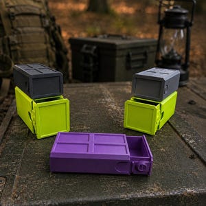 Pu&ograve; includere: Tre contenitori rettangolari con cassetti scorrevoli. Due contenitori hanno una base verde lime con un coperchio grigio scuro, mentre il terzo &egrave; interamente viola. Ogni coperchio presenta un motivo a griglia e un pomello laterale.