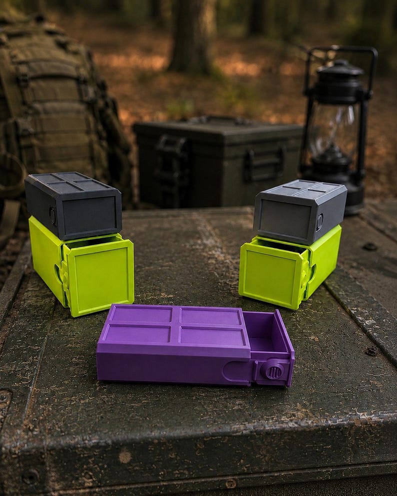 Pu&ograve; includere: Tre contenitori rettangolari con cassetti scorrevoli. Due contenitori hanno una base verde lime con un coperchio grigio scuro, mentre il terzo &egrave; interamente viola. Ogni coperchio presenta un motivo a griglia e un pomello laterale.