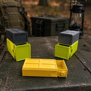Pu&ograve; includere: Tre contenitori rettangolari con cassetti scorrevoli. Due contenitori sono impilati con coperchi grigio scuro e basi verde lime, mentre un contenitore giallo &egrave; posizionato in piano. Ogni unit&agrave; presenta un motivo a griglia sulla parte superiore.
