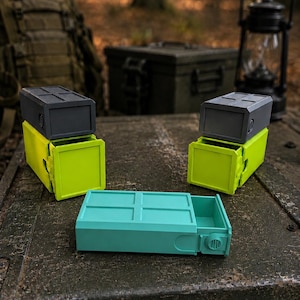 Pu&ograve; includere: Tre contenitori rettangolari con cassetti scorrevoli. Due contenitori sono impilati con coperchi grigio scuro e basi verde lime. Un contenitore turchese &egrave; posizionato in piano davanti. Ognuno presenta un motivo a griglia sulla parte superiore.