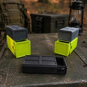 Pu&ograve; includere: Tre contenitori rettangolari con cassetti scorrevoli. Due contenitori presentano una parte superiore grigio scuro con un cassetto verde lime brillante, mentre il terzo &egrave; interamente grigio scuro. Ogni unit&agrave; ha una parte superiore a griglia.
