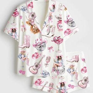 Könnte beinhalten: Weißes Pyjama-Set mit einem sich wiederholenden Muster aus rosa Cowboyhüten, Stiefeln, Gitarren, Discokugeln und Cocktailgläsern. Das Set enthält ein Hemd mit Knöpfen und rosa Besatz sowie passende Shorts. Das Wort "Tegu" ist auf einer Flasche aufgedruckt.