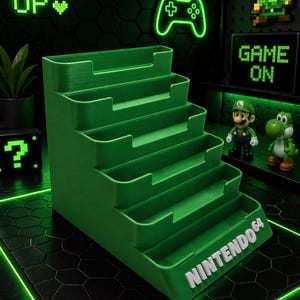 Puede incluir: Un organizador verde escalonado con el texto "NINTENDO 64" en blanco. El organizador está diseñado para parecerse a escalones. El fondo presenta una decoración con temática de juegos en verde neón, incluyendo un mando y las palabras "LEVEL UP" y "GAME ON".
