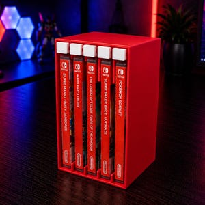 May include: A red plastic storage rack holding five Nintendo Switch game cases vertically. The games include Super Mario Party Jamboree, Mario Kart 8 Deluxe, The Legend of Zelda: Tears of the Kingdom, Super Smash Bros. Ultimate, and Pokémon Scarlet.