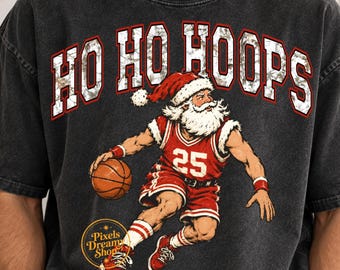 May include: A charcoal grey crewneck t-shirt featuring a graphic of Santa Claus in a red basketball uniform with the number 25, dribbling a basketball. Above the graphic, the text reads HO HO HOOPS in white with red outlines.